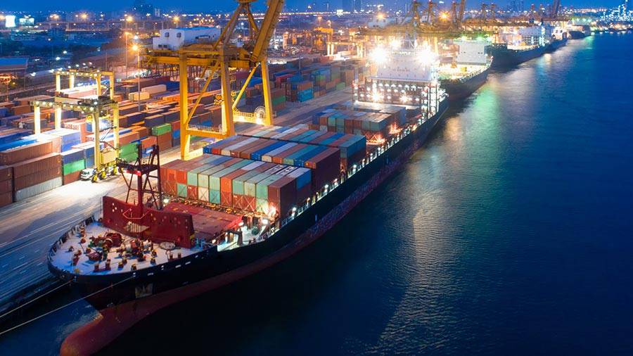 Container ship loading at a lit port terminal at night